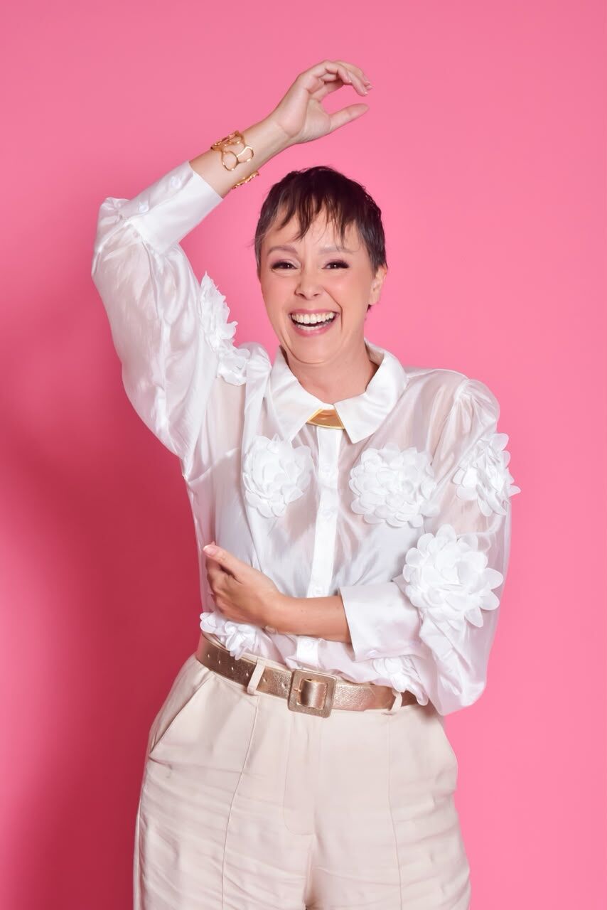 Mulher sorrindo com blusa branca com flores